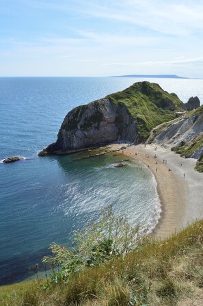 A coastal beach with a rocky cliff and a clear view of the sea.