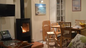 A cozy living room with a fireplace, wooden furniture, and a television. - Unique detached holiday cottage, Hampshire  (Sopley)