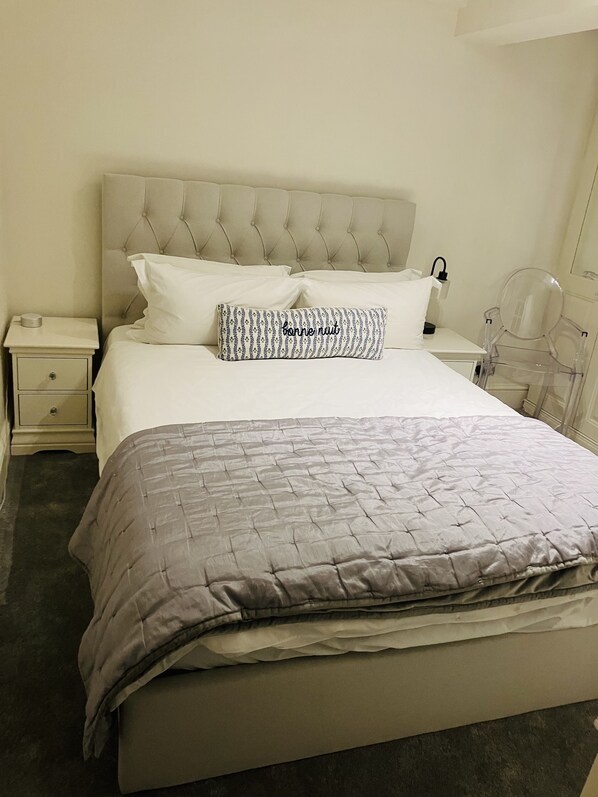 A neatly made bed with a tufted headboard, a patterned pillow, and a bedside lamp. - Charming Living In Central London - (3 Bed / 3 Bath) (London)