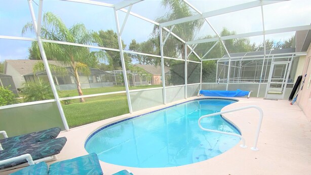A covered swimming pool with lounge chairs and a view of the surrounding neighborhood. - Luxury Villa with Private Pool 8 miles from Disney & near golf (CLERMONT)