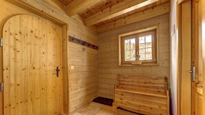 Un interior de madera con una puerta grande, un banco, una ventana y un suelo de baldosas.