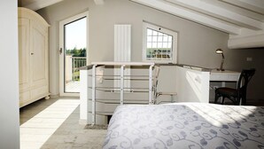 A bedroom with a bed, a desk, a chair, a wardrobe, a window, and a balcony.