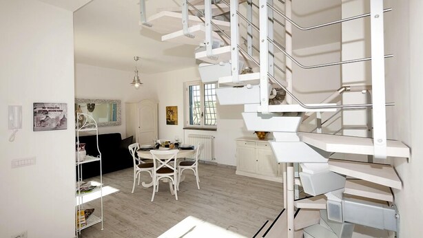 A modern interior with a spiral staircase, a dining area, and a kitchen.