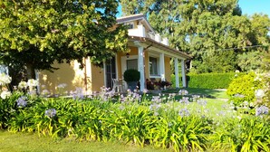 A house with a porch, surrounded by a garden with various flowers and greenery.