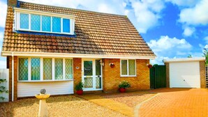 A two-story house with a tiled roof, a front garage, and a driveway leading to the entrance. - Stunning Romantic Cottage ★ nr Beach & Attractions ★Large Garden ★ Pet Friendly! (Chapel Saint Leonards)