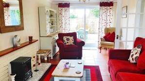 A living room with a red sofa, a red armchair, a wooden coffee table, and a white cabinet. - Stunning Romantic Cottage ★ nr Beach & Attractions ★Large Garden ★ Pet Friendly! (Chapel Saint Leonards)