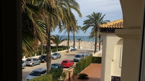 Uitzicht op een parkeerplaats met auto's, palmbomen en een strand op de achtergrond.