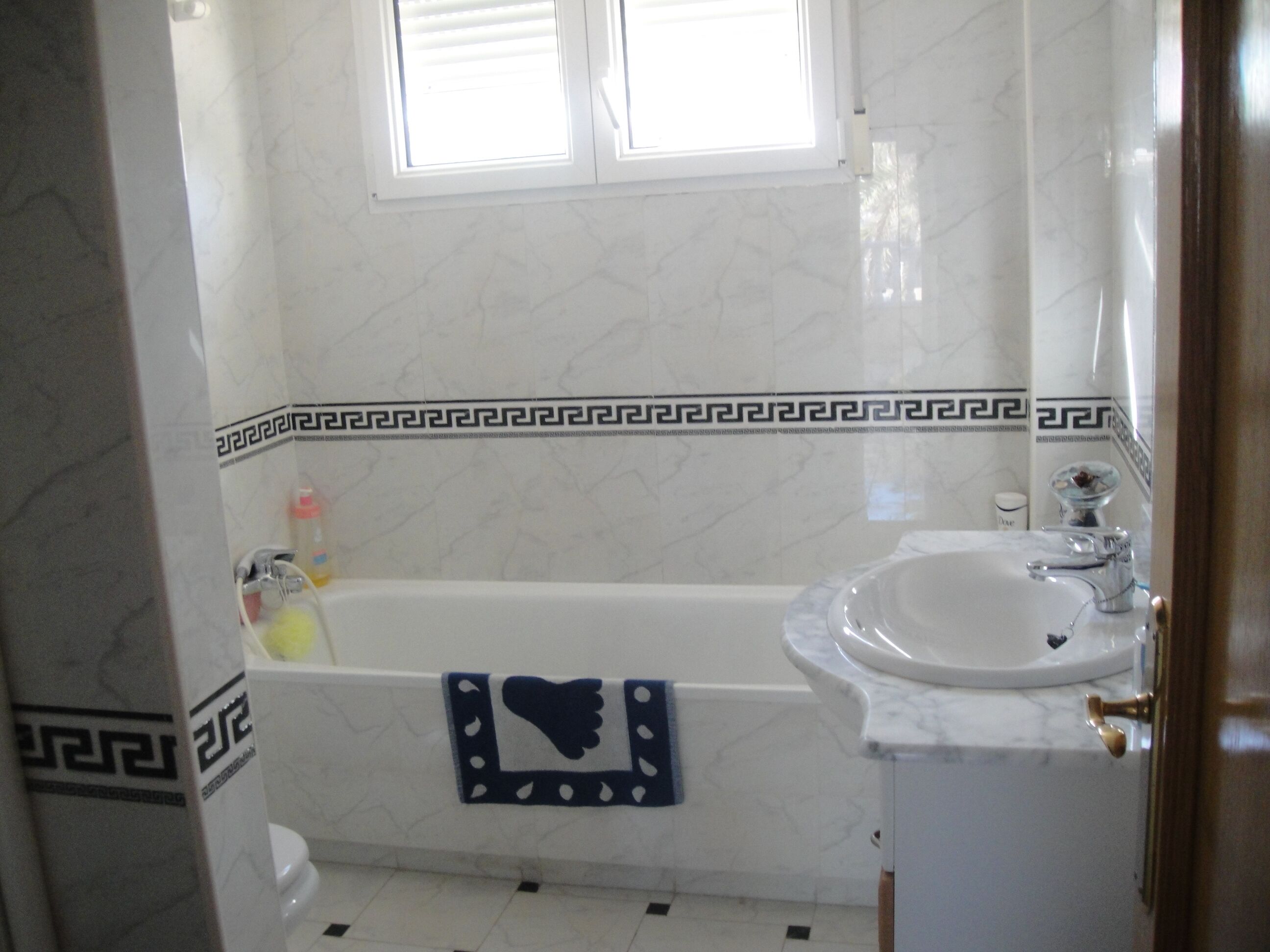 A bathroom with a bathtub, a sink, and a window.
