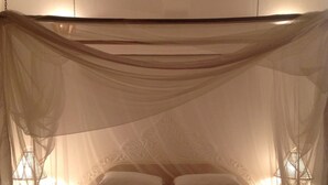 Ein Himmelbett, weiße Bettwäsche und ein Deckenventilator.