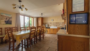 Une cuisine avec des armoires en bois, une table à manger avec des chaises, un ventilateur de plafond et un certificat encadré accroché au mur.