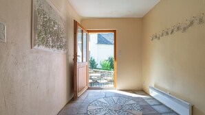 Un couloir carrelé qui mène à une porte ouverte donnant sur un balcon.