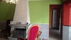 A room with a stone fireplace, a red chair, and a chandelier. - Beautiful, luxurious farmhouse In Champagne. Only 1 Hr From Paris, Near Epernay. (Baslieux-Sous-Châtillon)