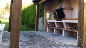 An outdoor barbecue area with a stone grill, wooden pergola, and a stone pathway. - Beautiful, luxurious farmhouse In Champagne. Only 1 Hr From Paris, Near Epernay. (Baslieux-Sous-Châtillon)