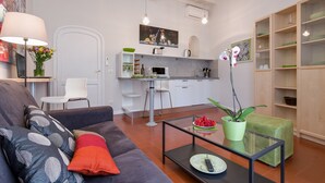 A modern living room with a sofa, coffee table, and a dining area with a kitchen in the background. - Grotta Pinta 7 | Cozy and romantic (Roma)