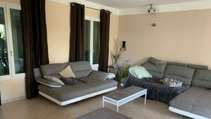 A modern living room with two grey sofas, a white coffee table, and a large window with curtains.