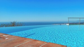 Une piscine à débordement à l’eau d’un bleu cristallin, offrant une vue sur l’océan.