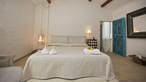Une chambre à coucher avec un lit, une table de chevet, une lampe suspendue et une porte bleue.