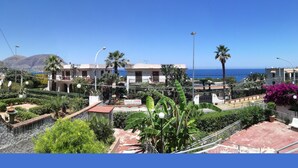 Ein Küstenwohngebiet mit freiem Blick auf das Meer, einem Brunnen und gepflegten Gärten.