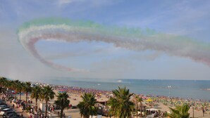 Une plage avec des palmiers et des parasols.