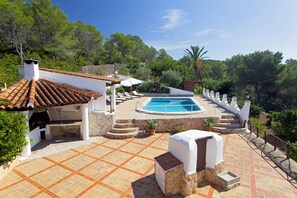 A rooftop pool with a stone deck, outdoor kitchen, and lounge chairs.
