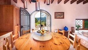 A dining area with a wooden table, chairs, a fruit bowl, and a view through an open archway. - Authentic Ibizan Charm in the Heart of the Island (Santa Eulalia des Riu)