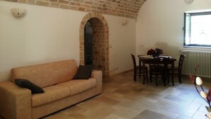 Un salon avec un plafond en briques, un canapé, une table à manger avec des chaises et une fenêtre donnant sur un beau paysage.