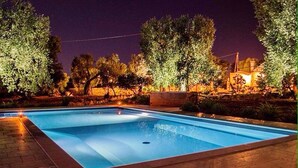 Une piscine rectangulaire dont les bords sont recouverts de carreaux, entourée d’une zone dallée.