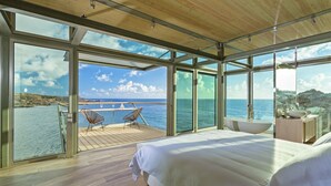 Une chambre à coucher moderne avec un grand lit, une terrasse en bois et une vue sur la mer.
