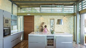 Une cuisine moderne dotée d’un îlot central, d’appareils électroménagers intégrés et de grandes fenêtres.