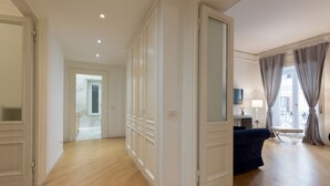 Une pièce spacieuse avec un plancher en bois, un canapé bleu foncé et une grande fenêtre avec des rideaux.