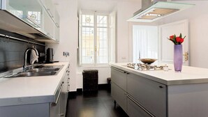 Une cuisine moderne dotée d’un îlot central, d’appareils électroménagers en acier inoxydable et d’une fenêtre laissant entrer la lumière naturelle.