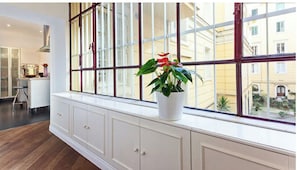 A room with a large window, a white cabinet with drawers, and a potted plant on the windowsill. - New Luxury Home in the heart of Rome (Roma)