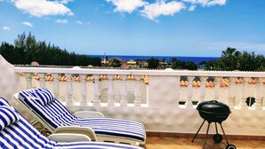 Terraza en la azotea con sillones de descanso y una parrilla.