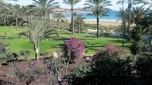 Campo de golf con palmeras y vistas a la playa.