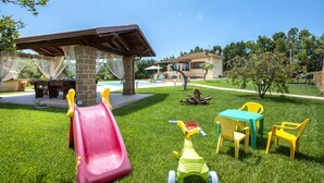 Un jardin avec un toboggan, une table de pique-nique et une petite table entourée de chaises.