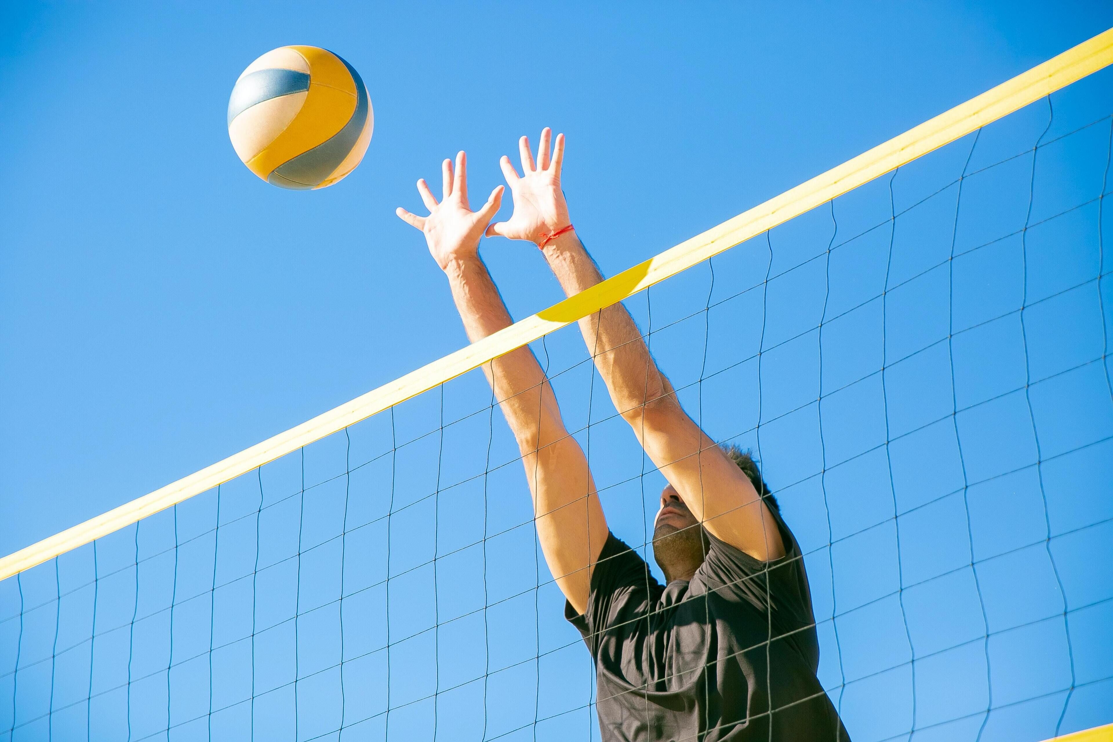 Una persona jugando voleibol, levantándose para golpear la pelota.