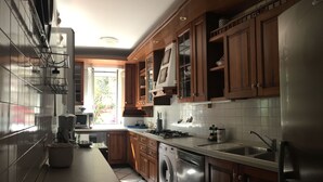 A modern kitchen with wooden cabinets, a stainless steel refrigerator, a dishwasher, and a large window providing natural light.
