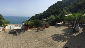 A terrace with outdoor seating, a pool, and a view of the sea.