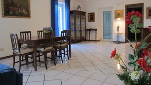 A dining area with a wooden table and chairs, a cabinet, and a vase of flowers.