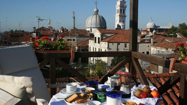 A table set with breakfast items and a view of historic buildings and a church tower.