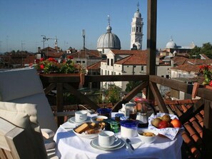 A table set with breakfast items and a view of historic buildings and a church tower. - Casa del Sole Bed & Breakfast - Panoramic loft in Venice city center (Venezia)