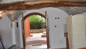 Vista del interior de una habitación con un arco de piedra que conduce a un espacio exterior.