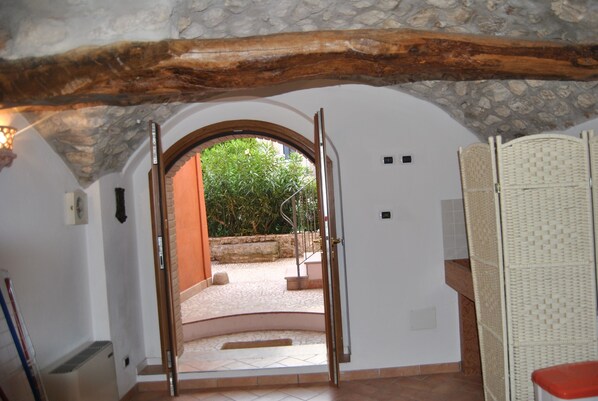 Vue intérieure d’une pièce avec une arche en pierre donnant sur un espace extérieur.