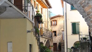 Una estrecha calle adoquinada flanqueada por edificios, un arco y macetas con plantas.