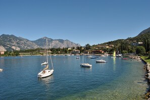 Un port de plaisance où sont amarrés plusieurs bateaux, entouré de montagnes et d’immeubles.