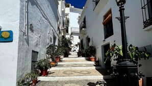 A narrow street with white buildings, potted plants, and a black street lamp. - Bahia del Mar  with dream views ,climatisation and wi-fi (Casares)