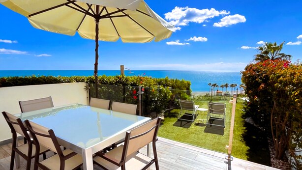 A patio with a glass table and chairs, an umbrella, and a view of the ocean. - Bahia del Mar  with dream views ,climatisation and wi-fi (Casares)