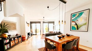 A modern living room with a wooden dining table, black chairs, a bookshelf, and a large painting on the wall. - Bahia del Mar  with dream views ,climatisation and wi-fi (Casares)