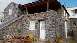 Un edificio in pietra con una scala in legno, un tavolo di legno e piante in vaso.