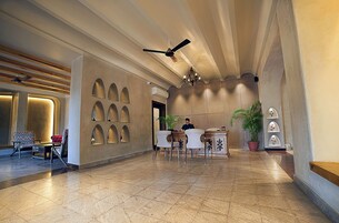 A hotel lobby with a reception desk, seating area, and a ceiling fan.